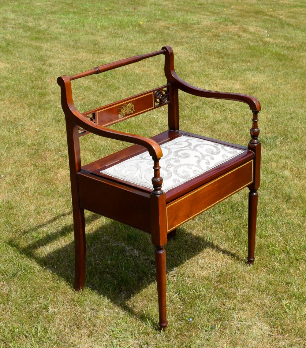 An Edwardian mahogany piano stool featuring marquetry inlay on the backrest, turned side handles, cream patterned upholstered lift-top seat, and tapered legs. View III