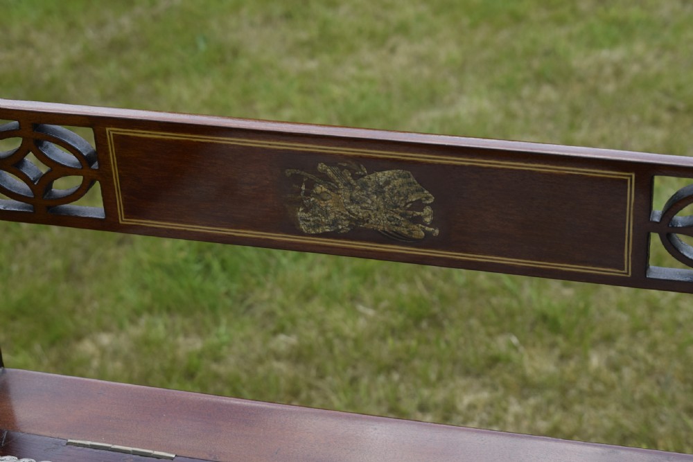 An Edwardian mahogany piano stool featuring marquetry inlay on the backrest, turned side handles, cream patterned upholstered lift-top seat, and tapered legs. View VII