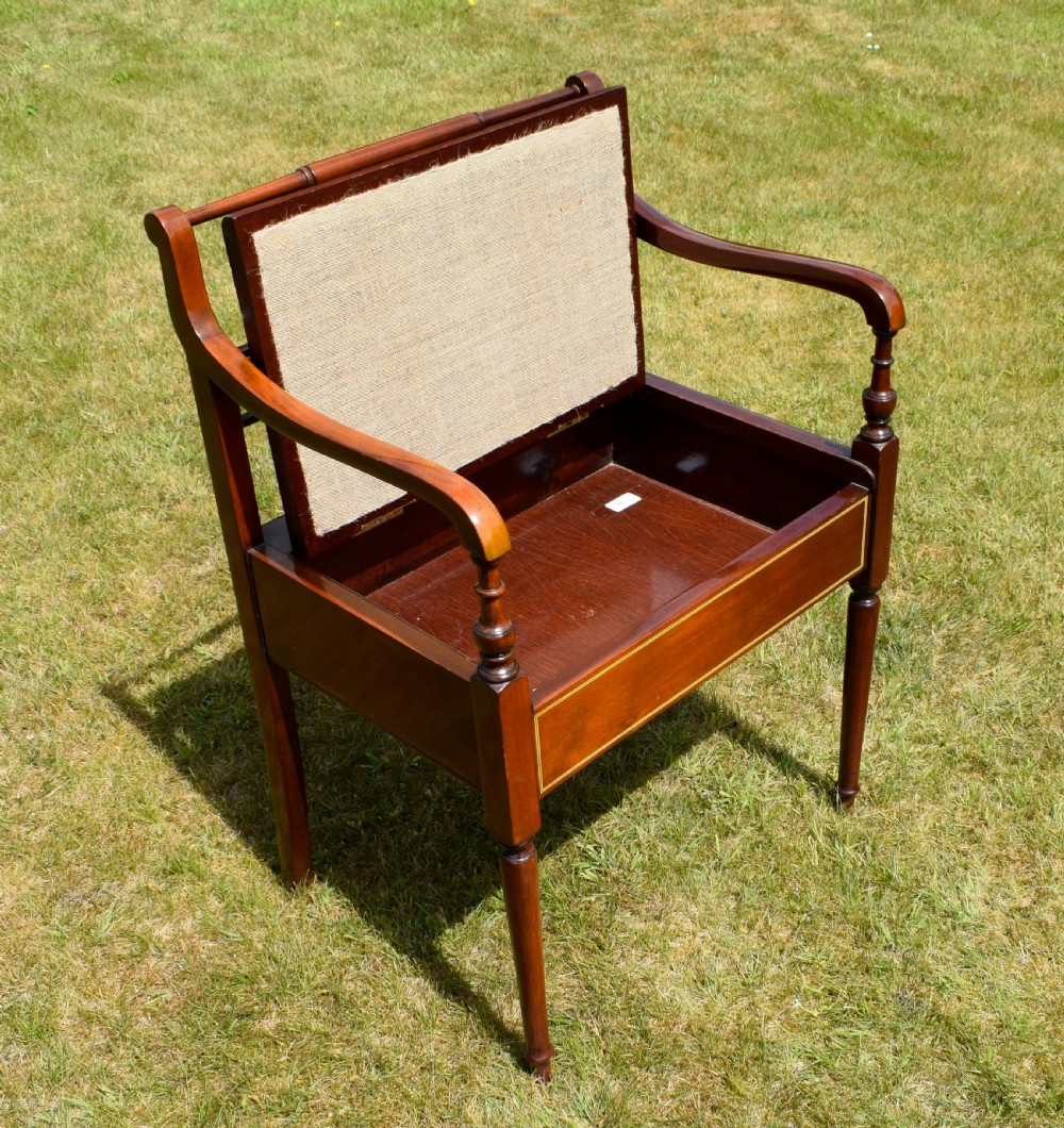 An Edwardian mahogany piano stool featuring marquetry inlay on the backrest, turned side handles, cream patterned upholstered lift-top seat, and tapered legs. View XII