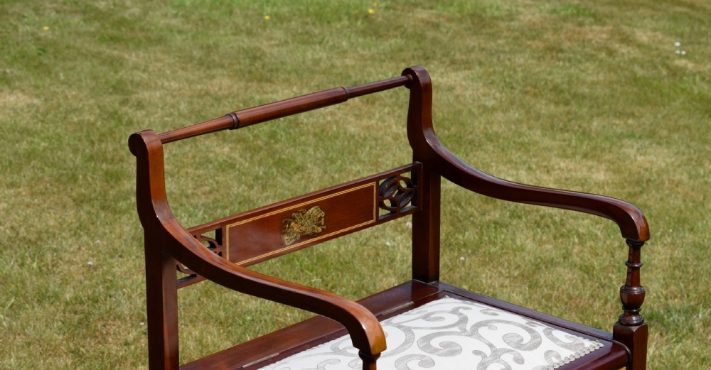 An Edwardian mahogany piano stool featuring marquetry inlay on the backrest, turned side handles, cream patterned upholstered lift-top seat, and tapered legs. View XIV