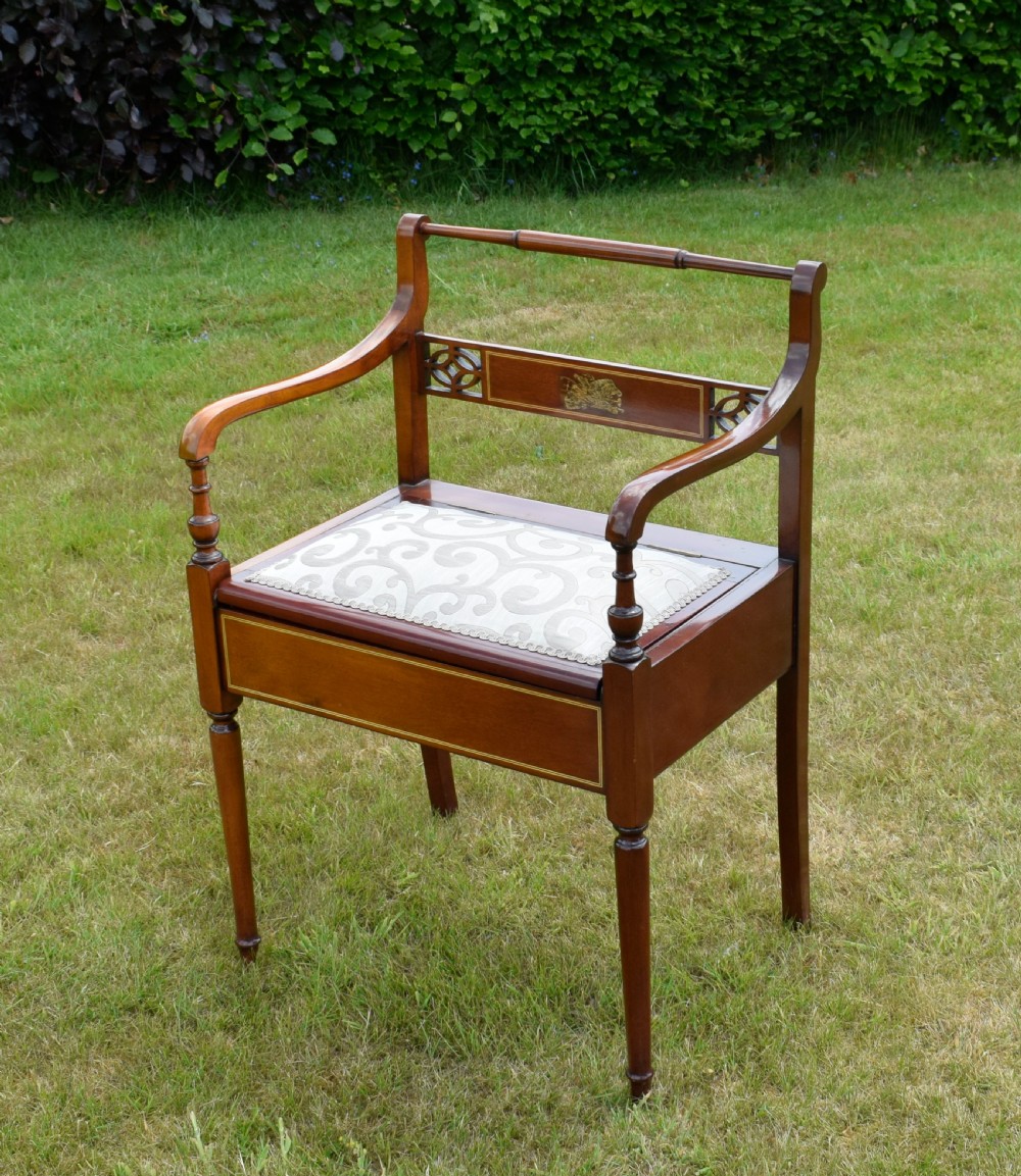 An Edwardian mahogany piano stool featuring marquetry inlay on the backrest, turned side handles, cream patterned upholstered lift-top seat, and tapered legs. View XVI