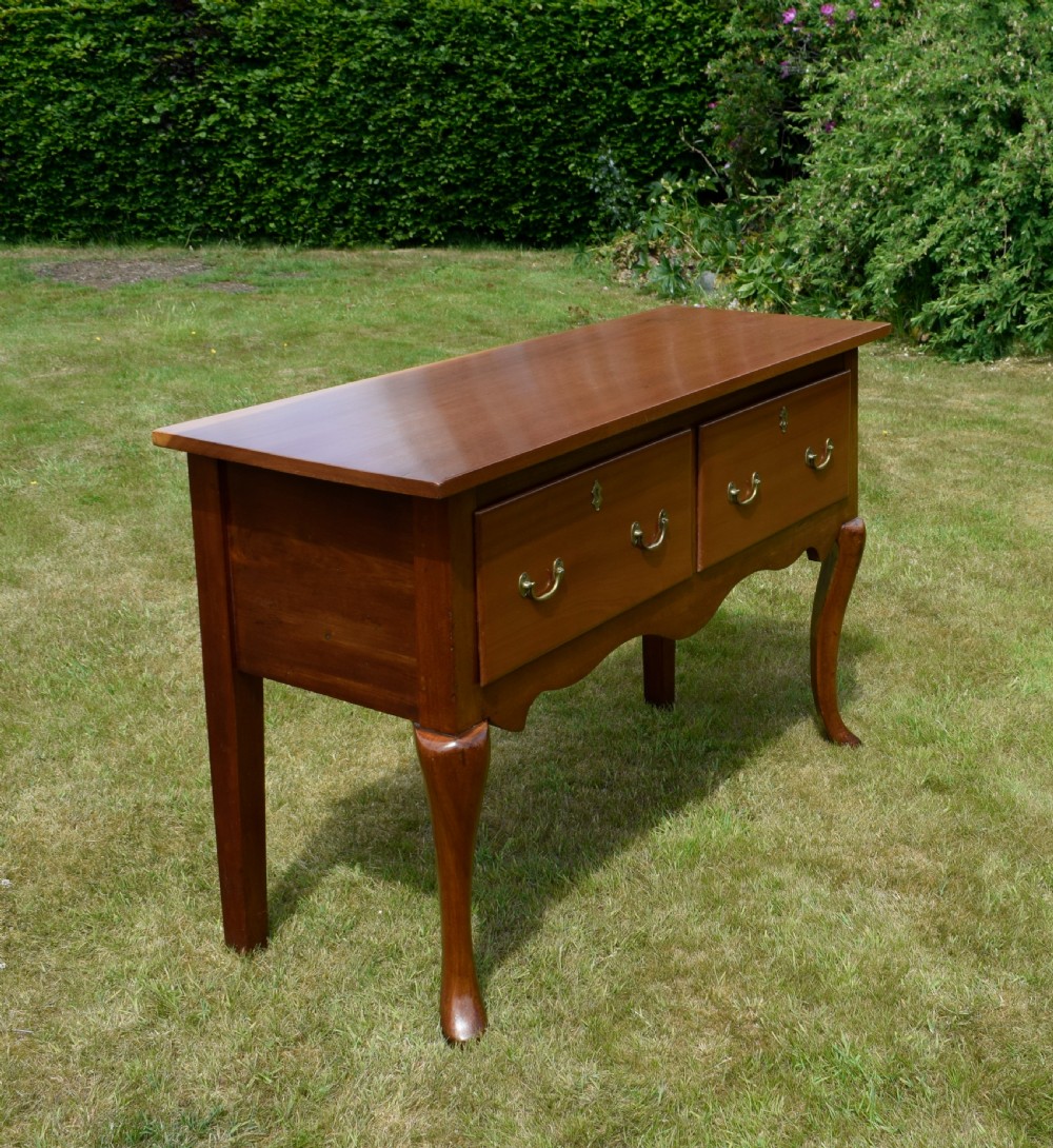 An antique mahogany dresser base featuring two drawers with brass handles, a scalloped apron, and front cabriole legs ending in pad feet. View II
