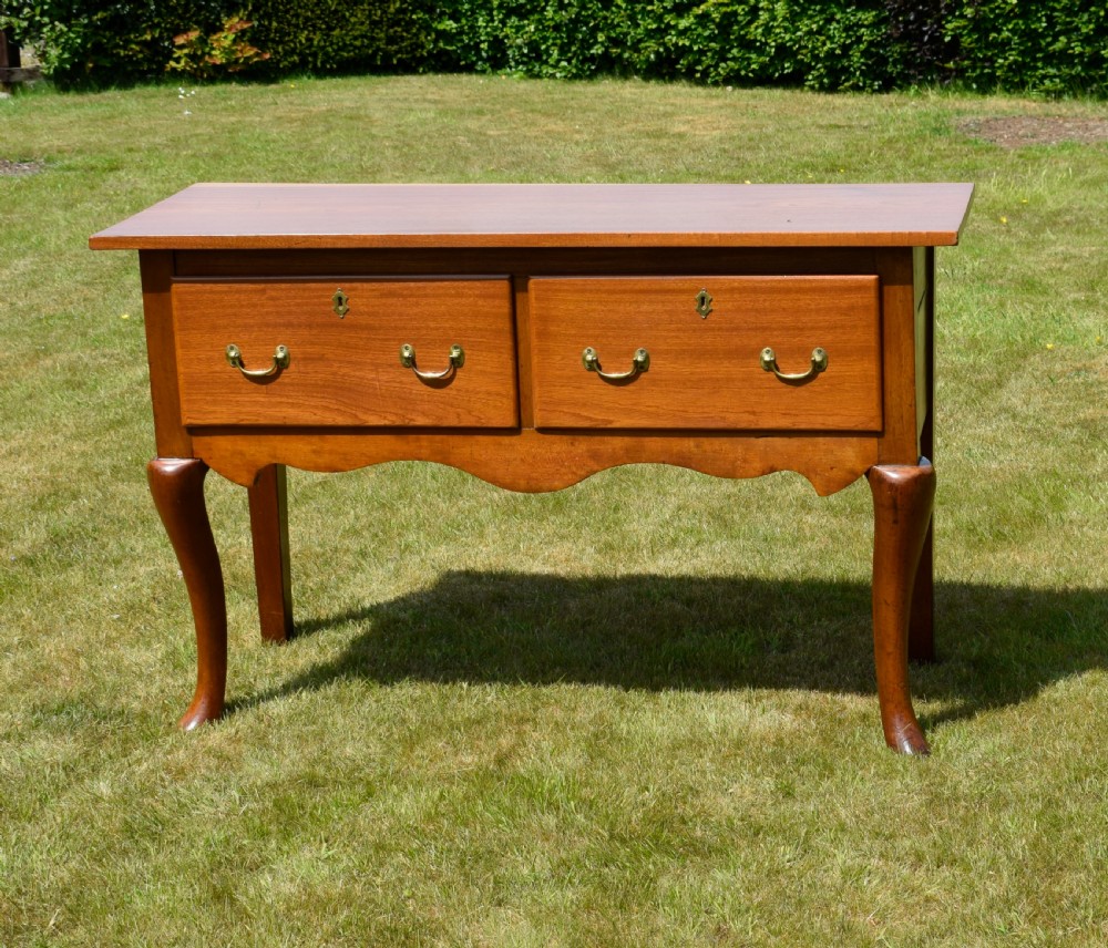 An antique mahogany dresser base featuring two drawers with brass handles, a scalloped apron, and front cabriole legs ending in pad feet. View III