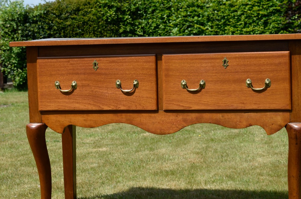 An antique mahogany dresser base featuring two drawers with brass handles, a scalloped apron, and front cabriole legs ending in pad feet. View V