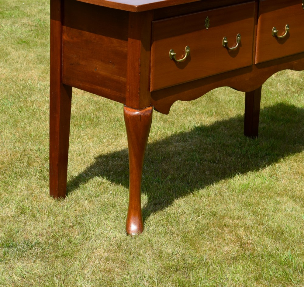 An antique mahogany dresser base featuring two drawers with brass handles, a scalloped apron, and front cabriole legs ending in pad feet. View VI