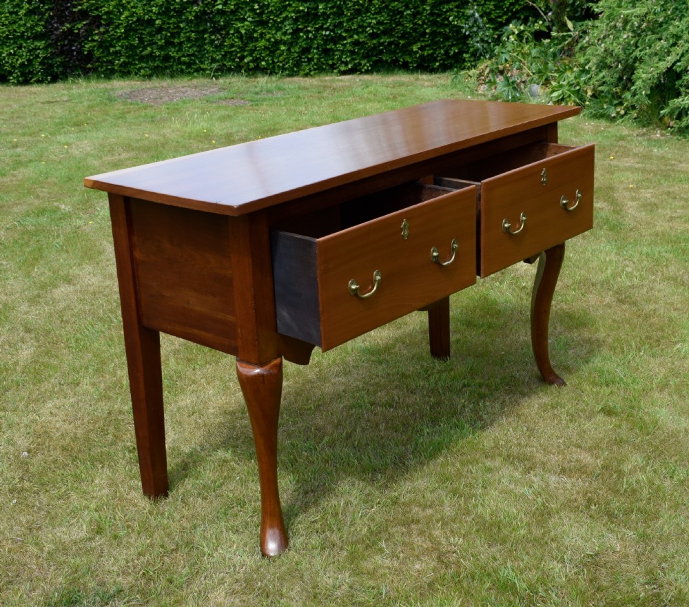An antique mahogany dresser base featuring two drawers with brass handles, a scalloped apron, and front cabriole legs ending in pad feet. View X