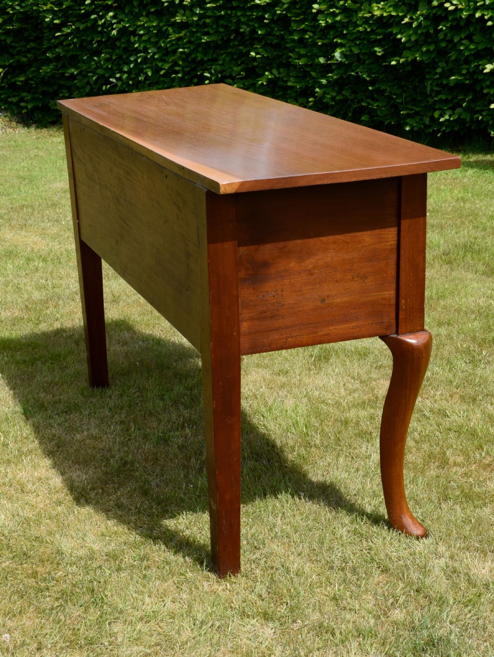 An antique mahogany dresser base featuring two drawers with brass handles, a scalloped apron, and front cabriole legs ending in pad feet. View XI