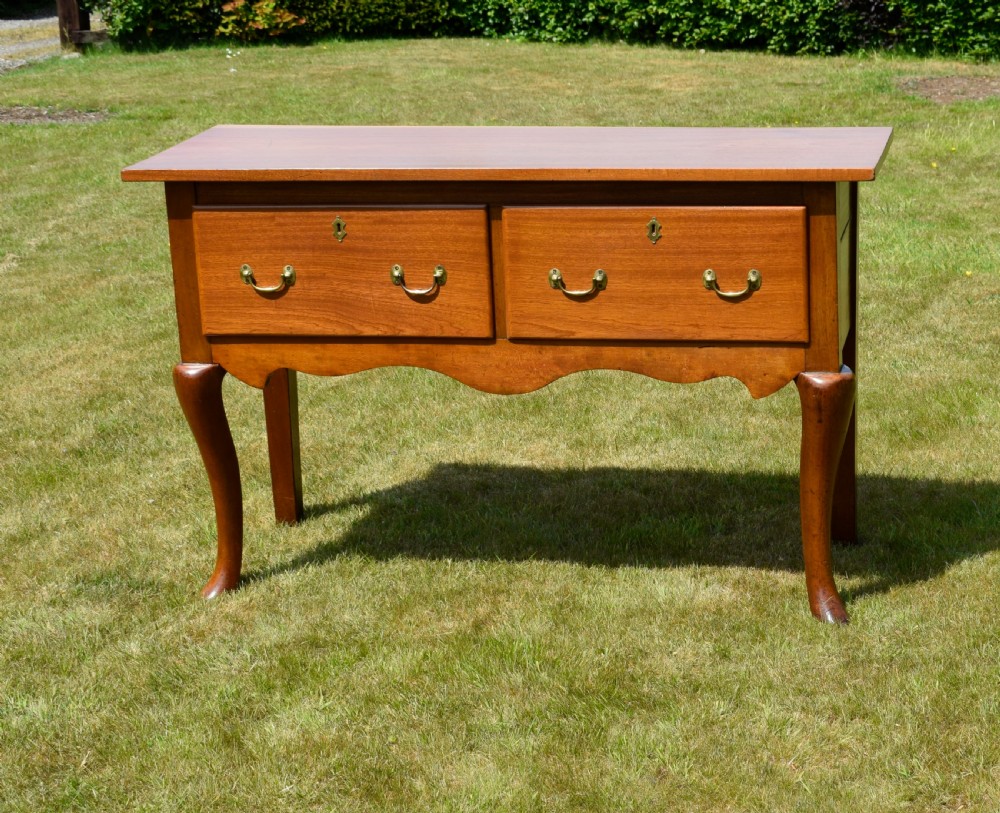An antique mahogany dresser base featuring two drawers with brass handles, a scalloped apron, and front cabriole legs ending in pad feet. View XII
