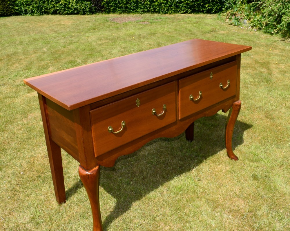 An antique mahogany dresser base featuring two drawers with brass handles, a scalloped apron, and front cabriole legs ending in pad feet. View XV