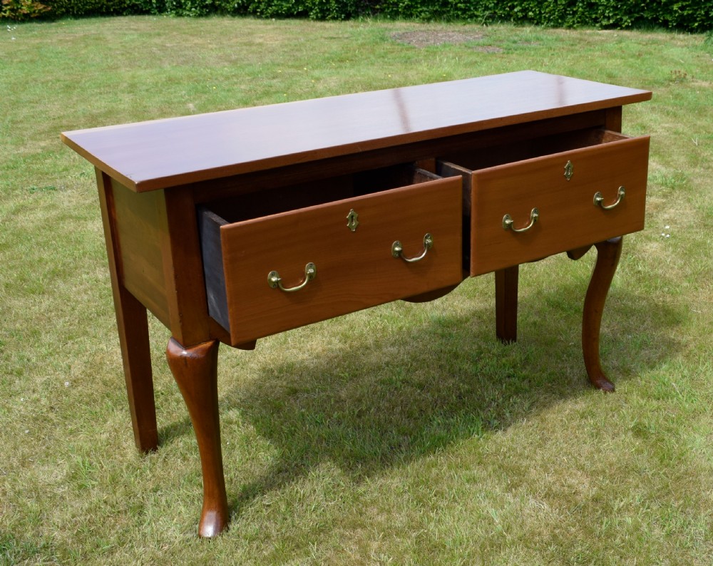 An antique mahogany dresser base featuring two drawers with brass handles, a scalloped apron, and front cabriole legs ending in pad feet. View XVIII