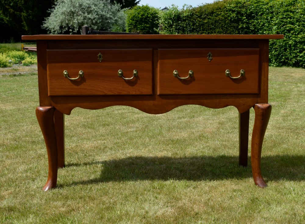 An antique mahogany dresser base featuring two drawers with brass handles, a scalloped apron, and front cabriole legs ending in pad feet. View XX