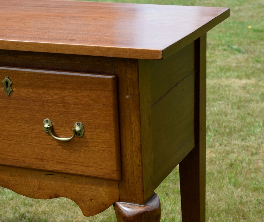 An antique mahogany dresser base featuring two drawers with brass handles, a scalloped apron, and front cabriole legs ending in pad feet. View XXI