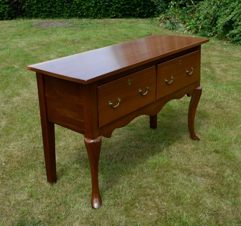 An antique mahogany dresser base featuring two drawers with brass handles, a scalloped apron, and front cabriole legs ending in pad feet. View XXV