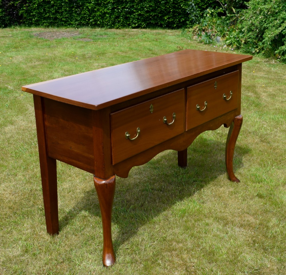 An antique mahogany dresser base featuring two drawers with brass handles, a scalloped apron, and front cabriole legs ending in pad feet. View XXVI