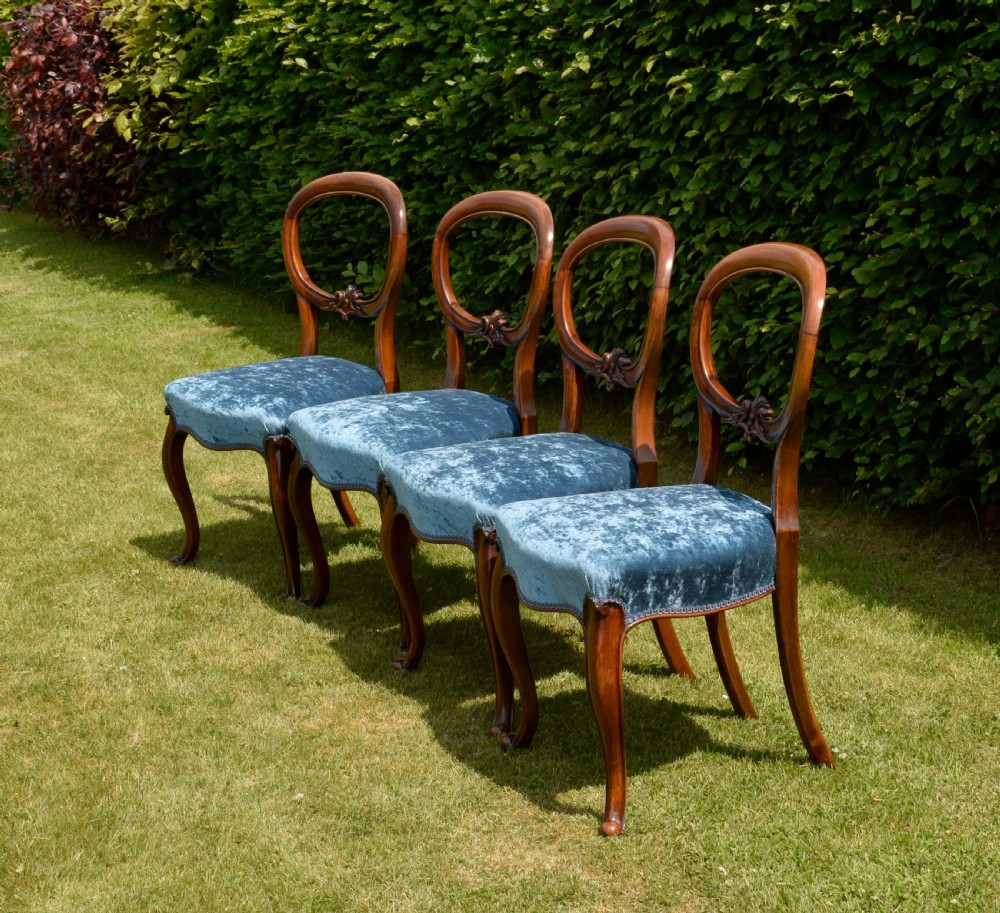 A set of four Victorian balloon back dining chairs crafted from polished walnut with blue velvet upholstered seats and carved crossbars above cabriole front legs. View IV
