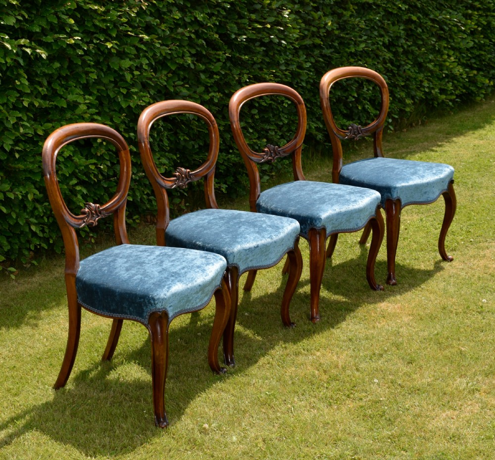A set of four Victorian balloon back dining chairs crafted from polished walnut with blue velvet upholstered seats and carved crossbars above cabriole front legs. View VII