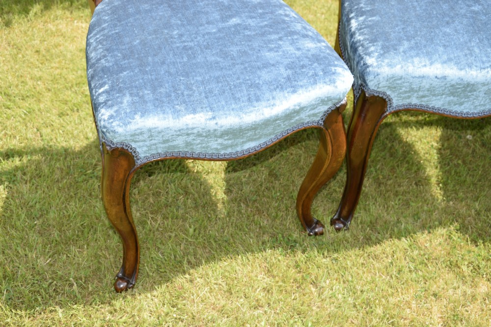 A set of four Victorian balloon back dining chairs crafted from polished walnut with blue velvet upholstered seats and carved crossbars above cabriole front legs. View IX