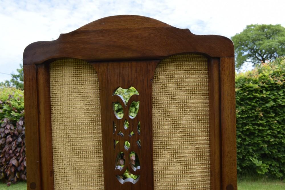 An Edwardian mahogany rocking chair featuring a crest rail with central marquetry inlay, double upholstered back panels, pierced fretwork splats, and light beige textured upholstery. View VII