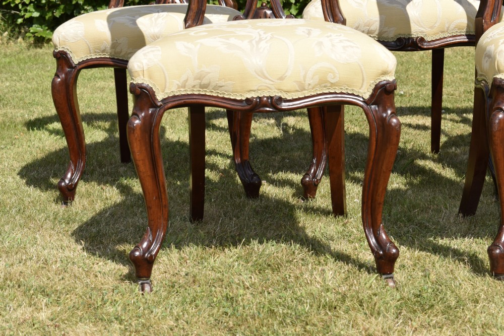 A set of five Victorian mahogany balloon back dining chairs with carved cabriole front legs and pale cream pattern-upholstered seats. View VII