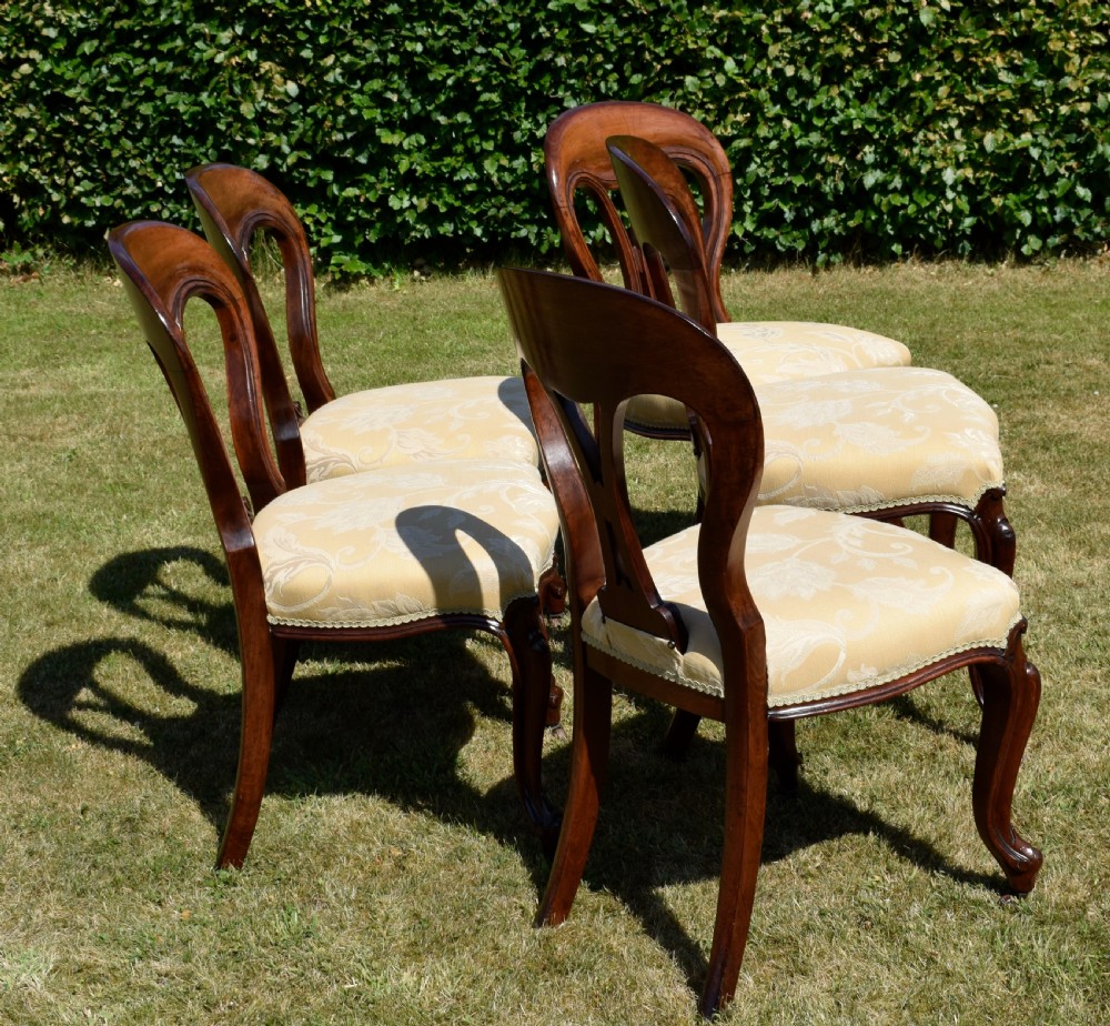 A set of five Victorian mahogany balloon back dining chairs with carved cabriole front legs and pale cream pattern-upholstered seats. View XII