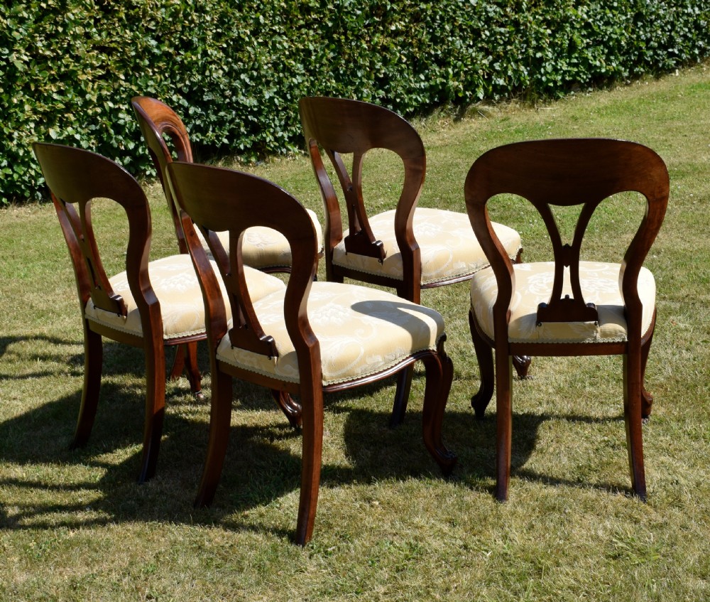 A set of five Victorian mahogany balloon back dining chairs with carved cabriole front legs and pale cream pattern-upholstered seats. View XIII