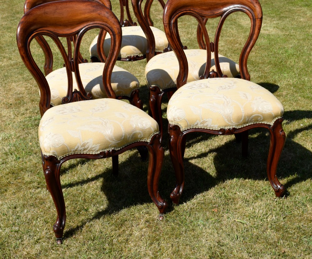 A set of five Victorian mahogany balloon back dining chairs with carved cabriole front legs and pale cream pattern-upholstered seats. View XVI