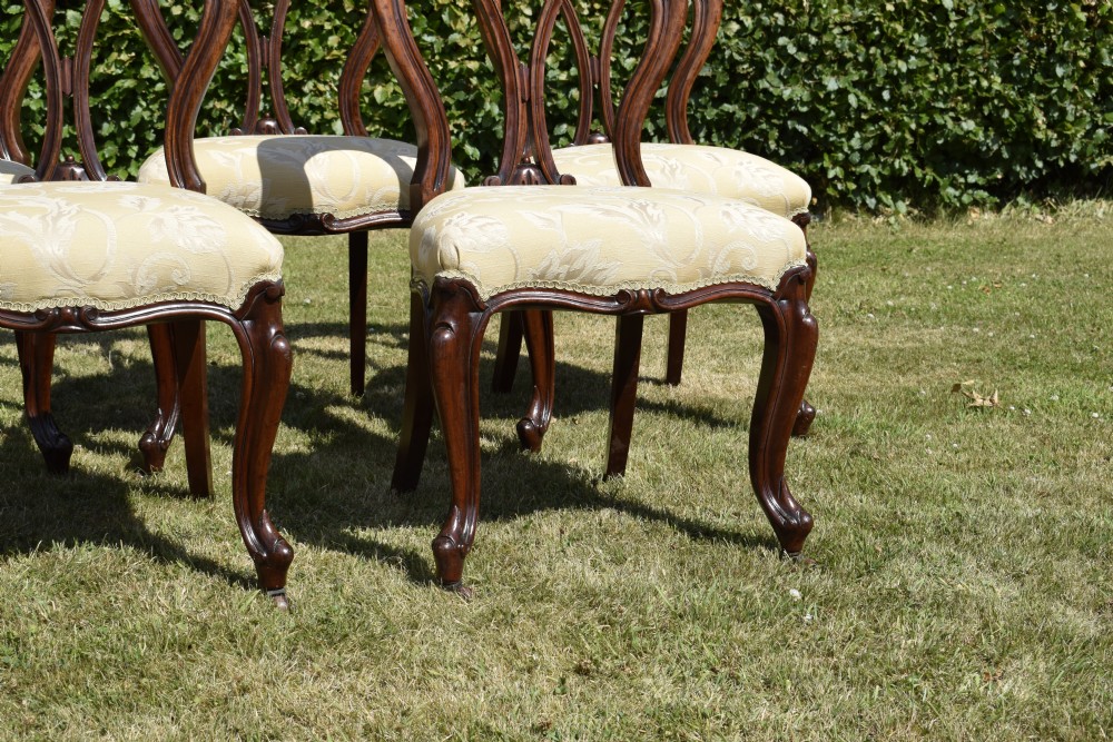 A set of five Victorian mahogany balloon back dining chairs with carved cabriole front legs and pale cream pattern-upholstered seats. View XVIII