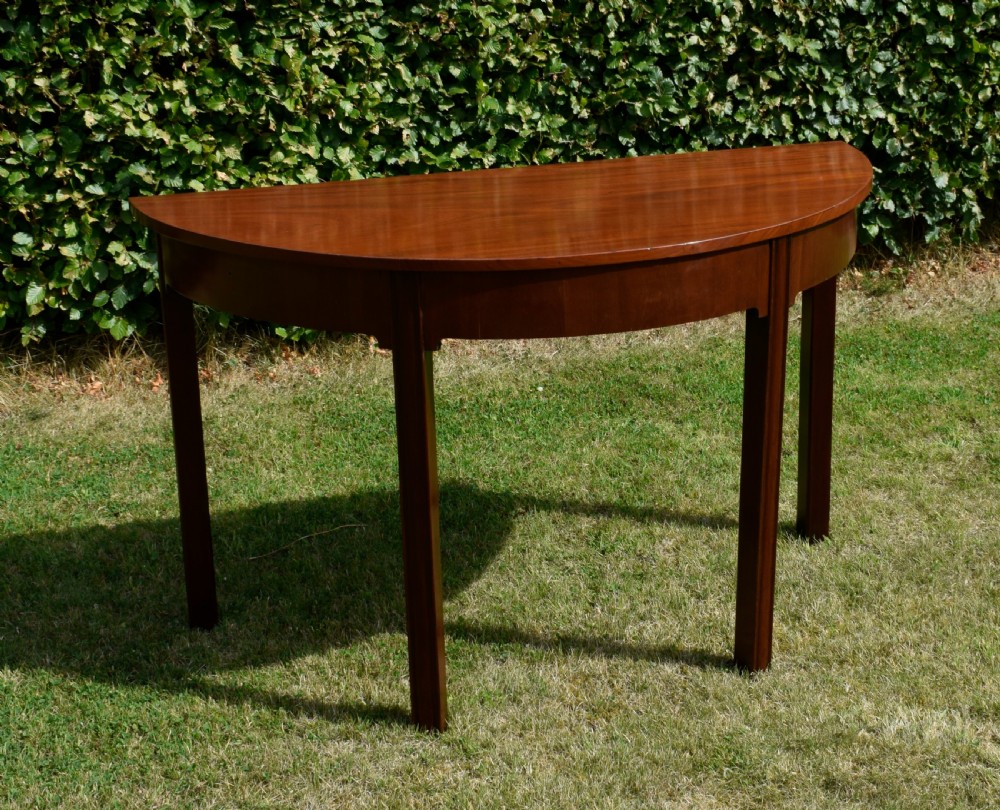 A Georgian mahogany demi-lune console table featuring a semi-circular top and four tapered legs. View II