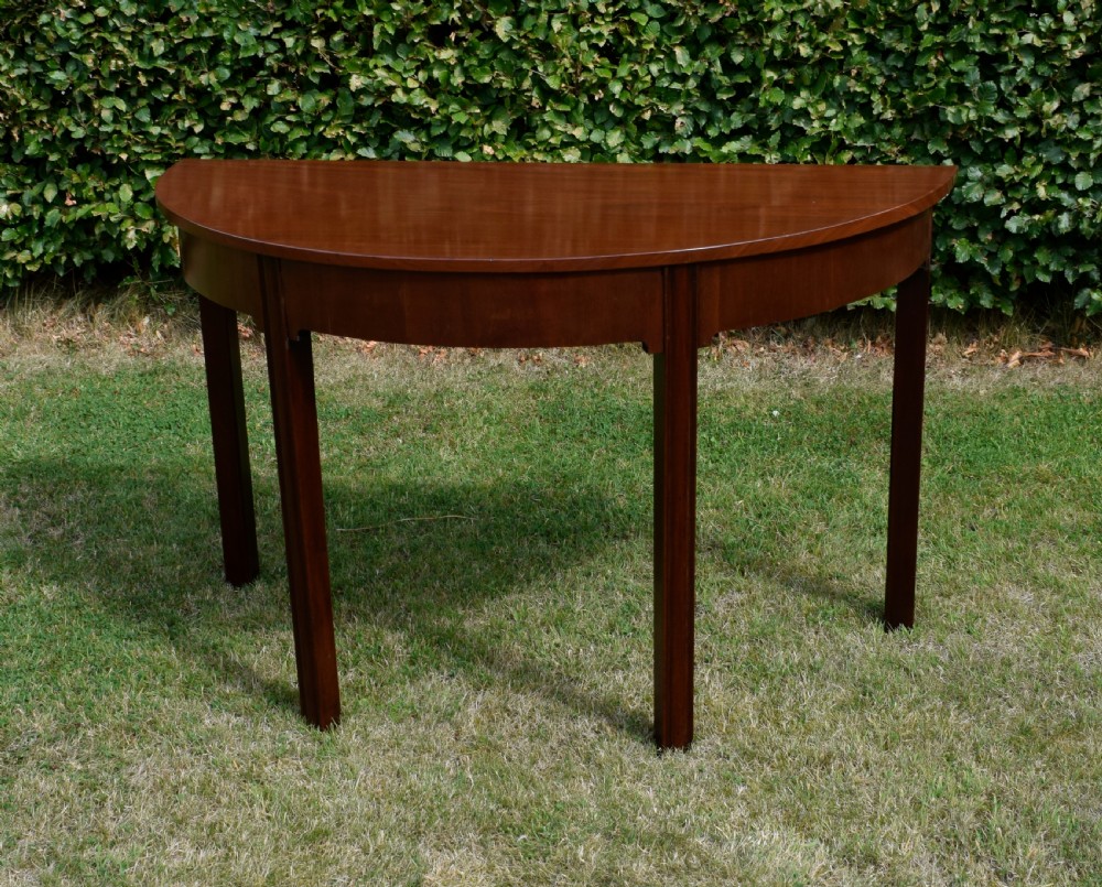 A Georgian mahogany demi-lune console table featuring a semi-circular top and four tapered legs. View VI