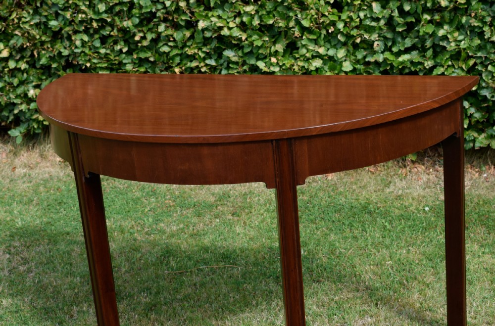 A Georgian mahogany demi-lune console table featuring a semi-circular top and four tapered legs. View VIII