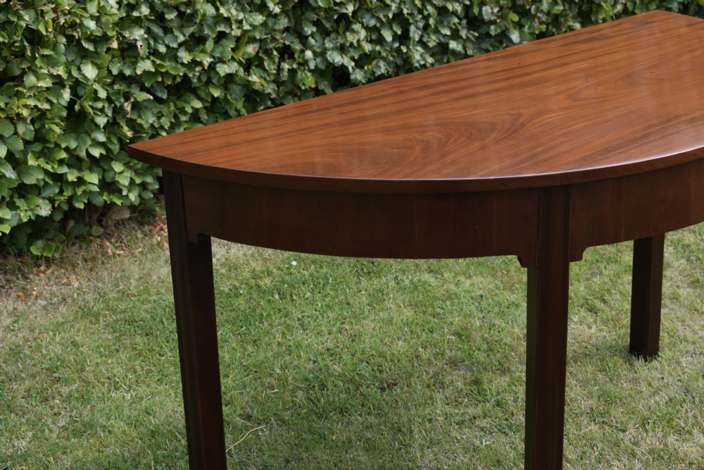 A Georgian mahogany demi-lune console table featuring a semi-circular top and four tapered legs. View XI