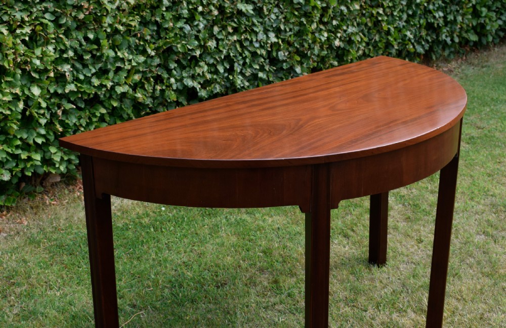 A Georgian mahogany demi-lune console table featuring a semi-circular top and four tapered legs. View XII