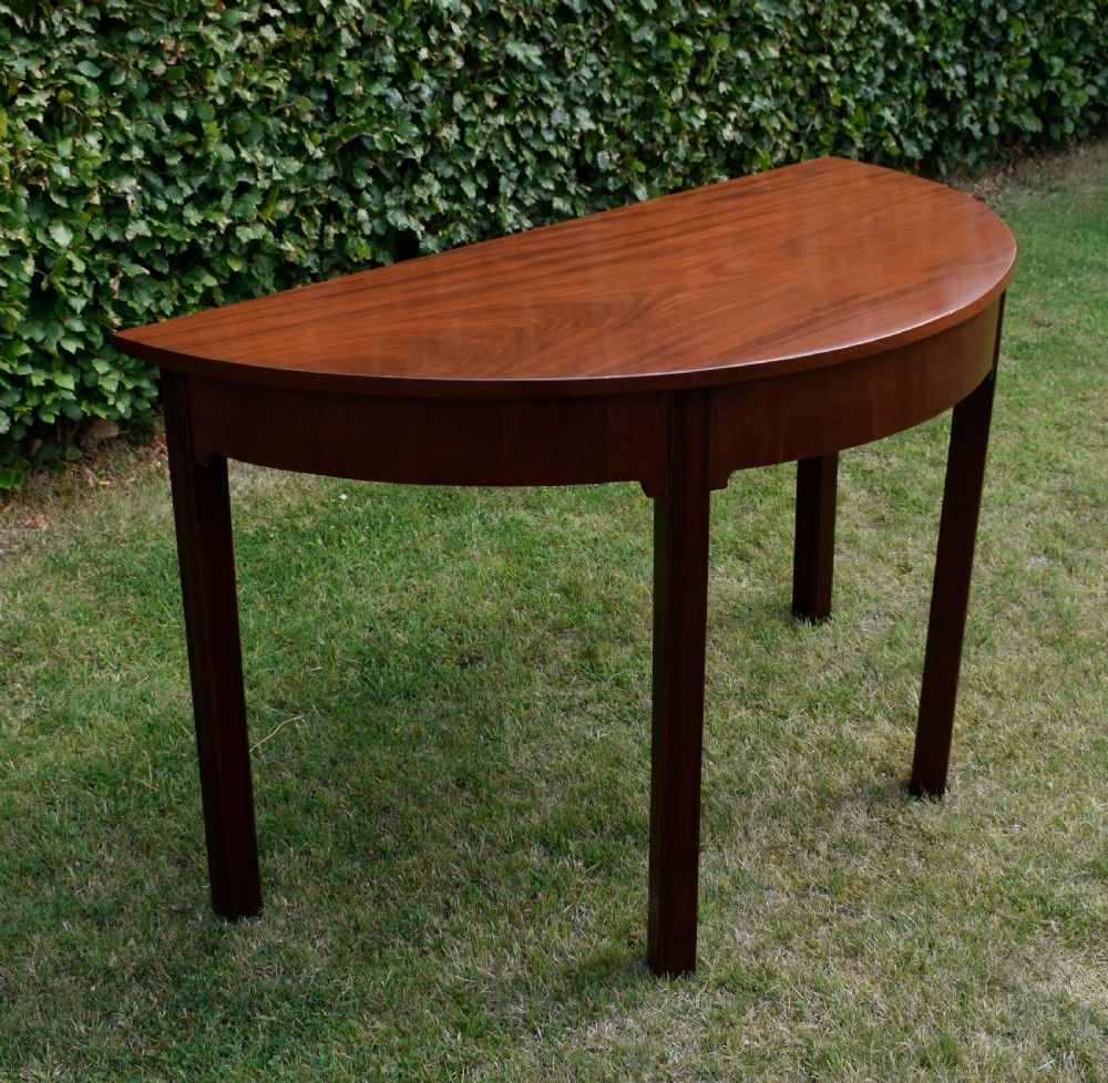 A Georgian mahogany demi-lune console table featuring a semi-circular top and four tapered legs. View XIII