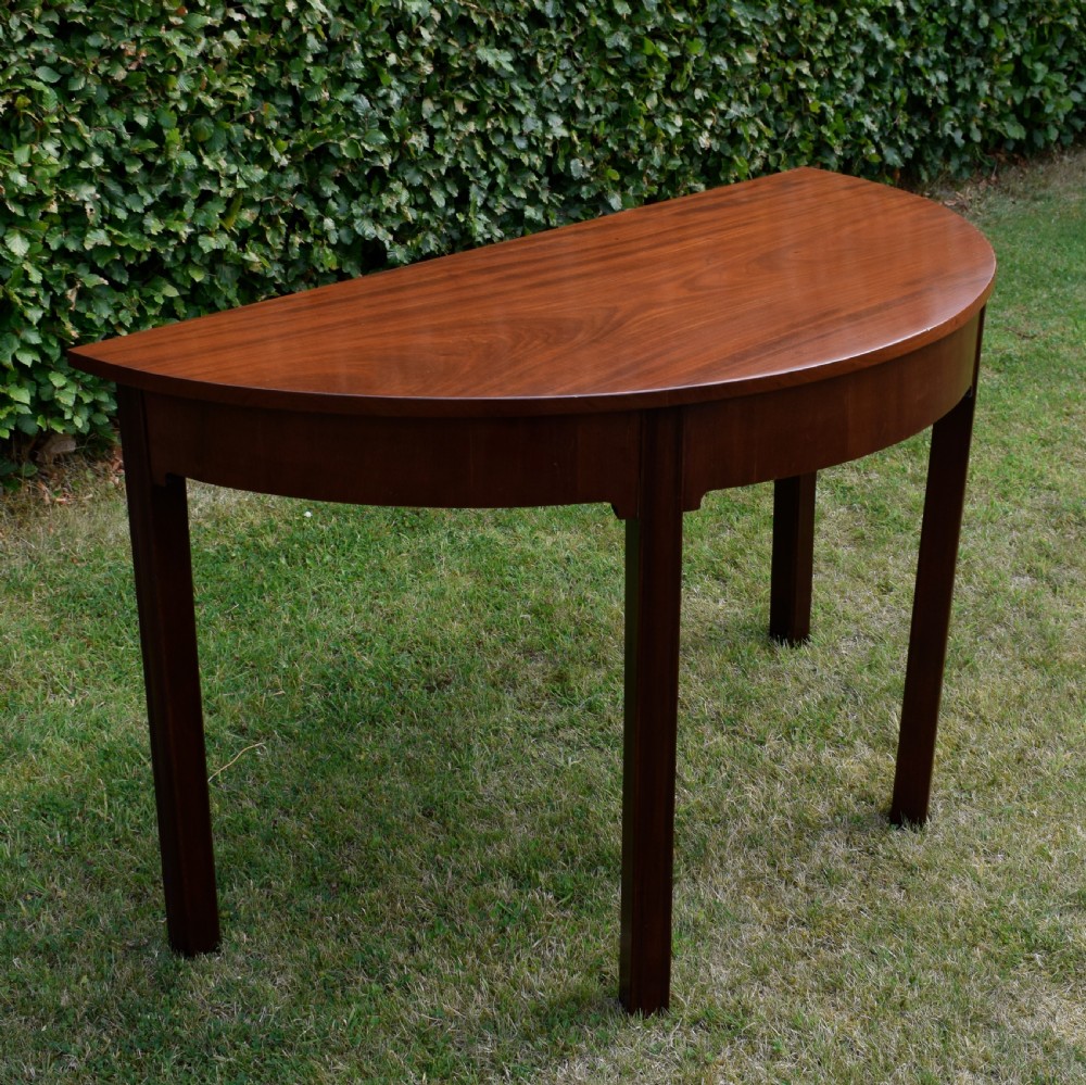 A Georgian mahogany demi-lune console table featuring a semi-circular top and four tapered legs. View XIV