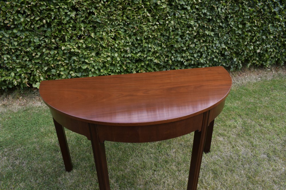 A Georgian mahogany demi-lune console table featuring a semi-circular top and four tapered legs. View XV