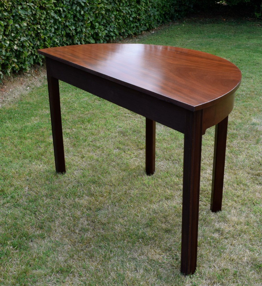 A Georgian mahogany demi-lune console table featuring a semi-circular top and four tapered legs. View XVII