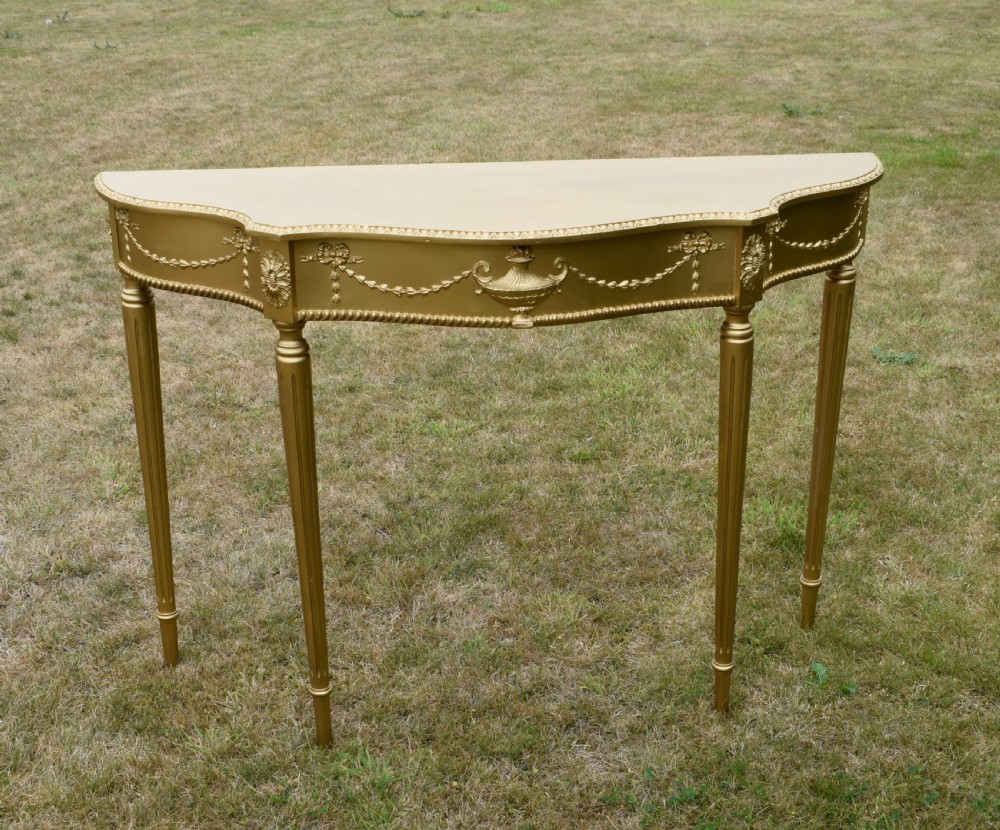 A gold gilded early twentieth-century console table featuring carved swags, a central urn motif, and fluted tapered legs. View II