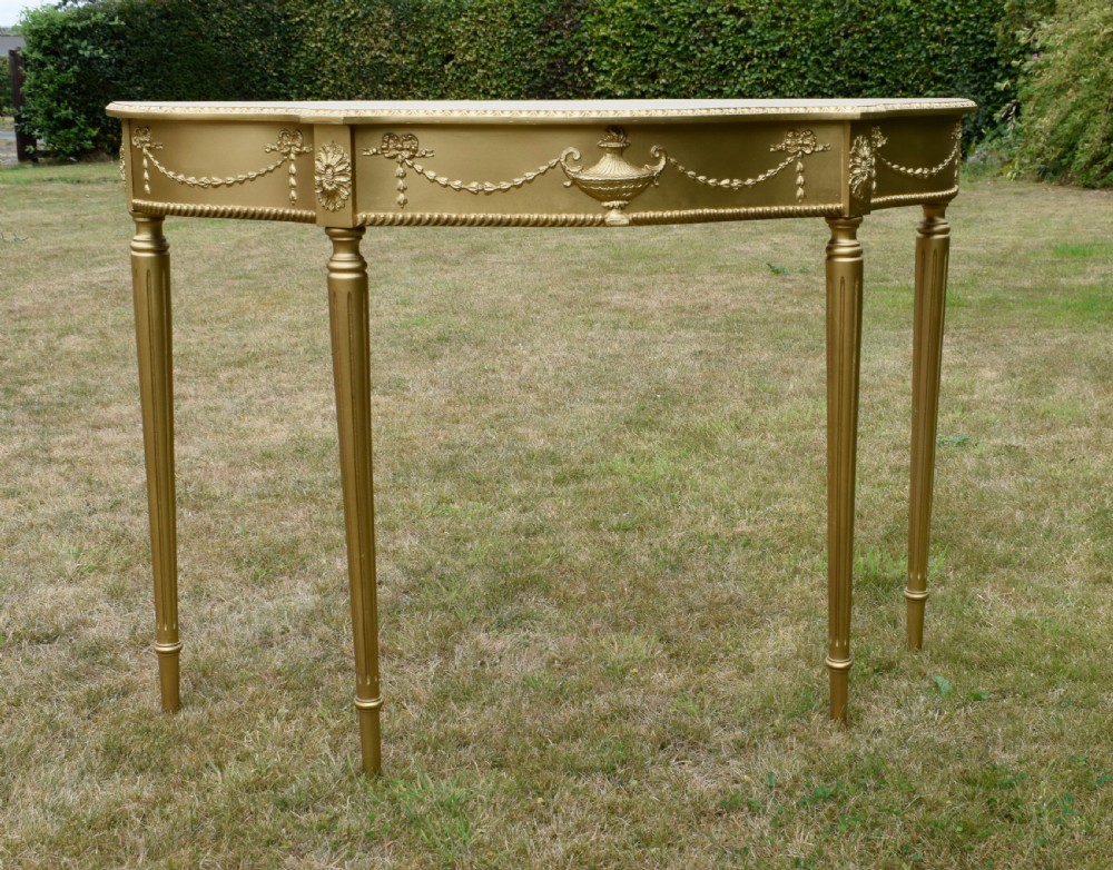 A gold gilded early twentieth-century console table featuring carved swags, a central urn motif, and fluted tapered legs. View VII