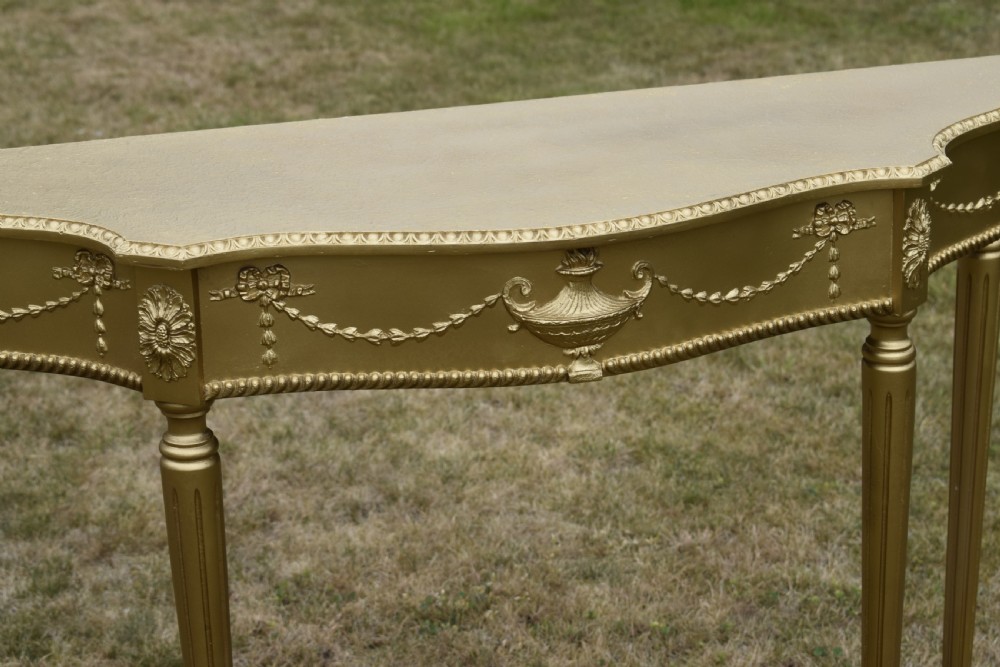 A gold gilded early twentieth-century console table featuring carved swags, a central urn motif, and fluted tapered legs. View VIII