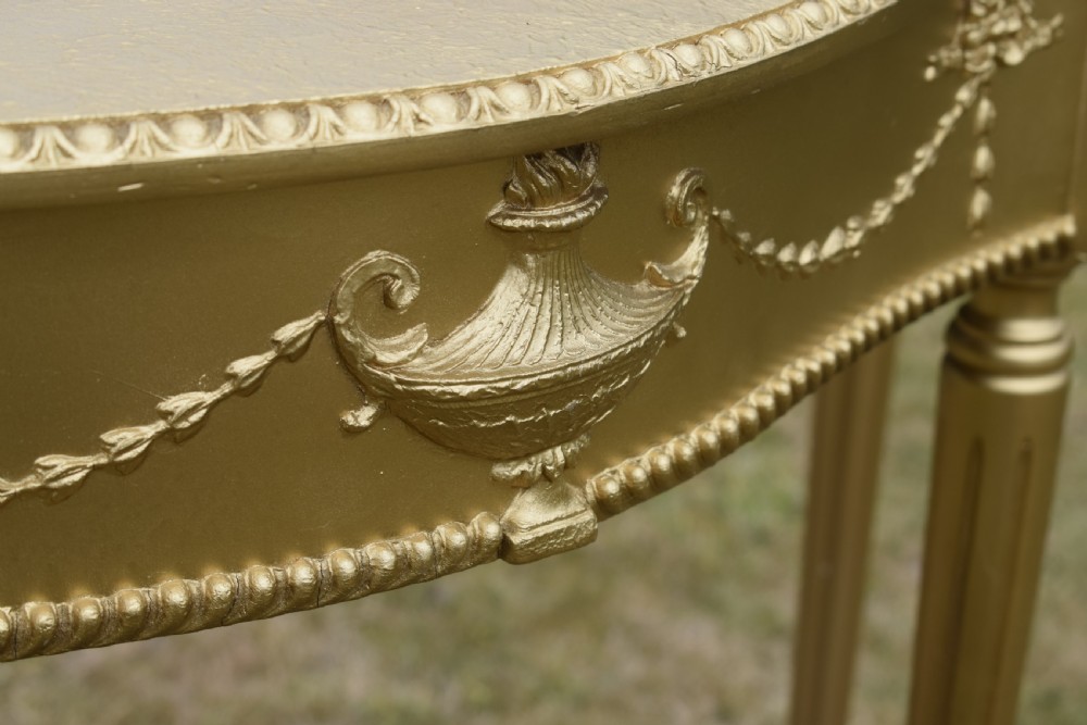 A gold gilded early twentieth-century console table featuring carved swags, a central urn motif, and fluted tapered legs. View XII