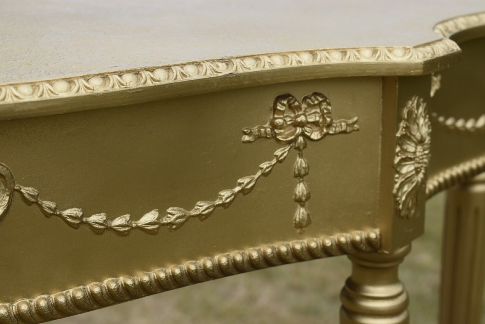 A gold gilded early twentieth-century console table featuring carved swags, a central urn motif, and fluted tapered legs. View XIV
