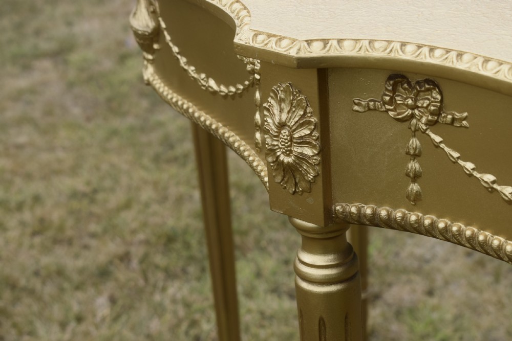A gold gilded early twentieth-century console table featuring carved swags, a central urn motif, and fluted tapered legs. View XVII