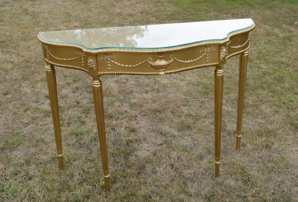 A gold gilded early twentieth-century console table featuring carved swags, a central urn motif, and fluted tapered legs. View XIX