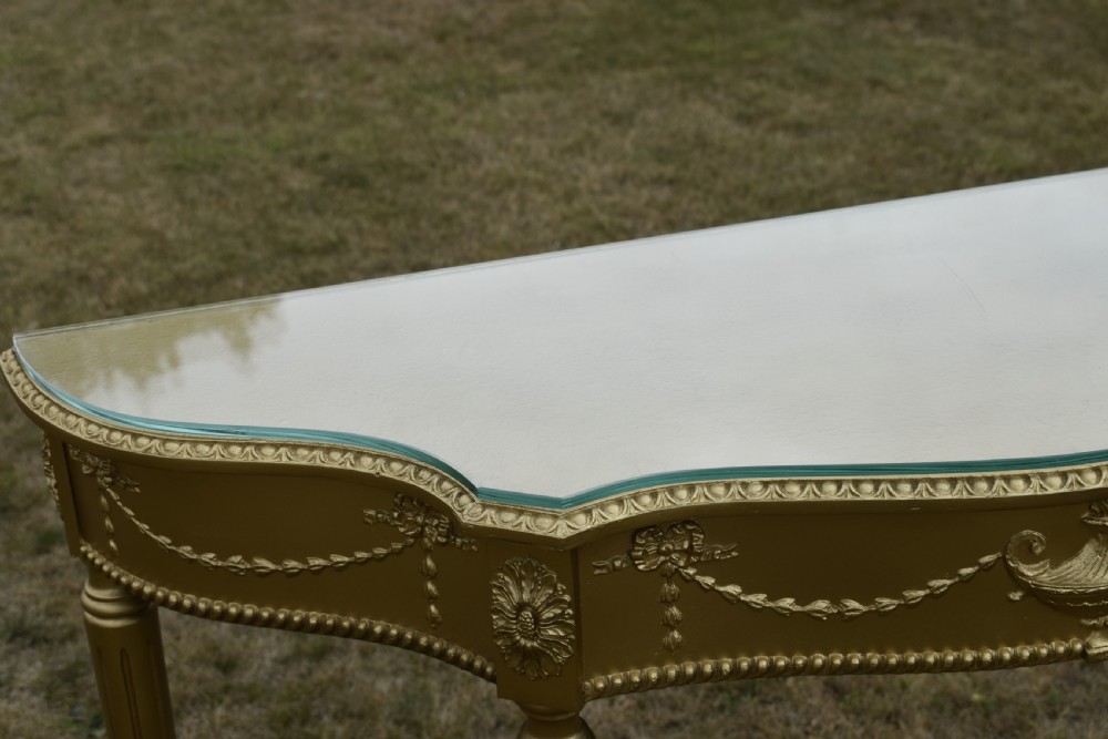 A gold gilded early twentieth-century console table featuring carved swags, a central urn motif, and fluted tapered legs. View XXII
