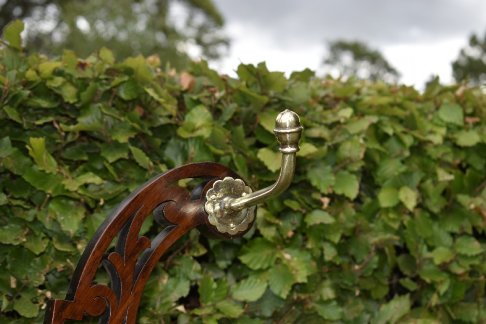 A Victorian walnut hall stand featuring carved fretwork branches, brass coat hooks, a central circular mirror, a glove box, and a lower drip tray base. View X