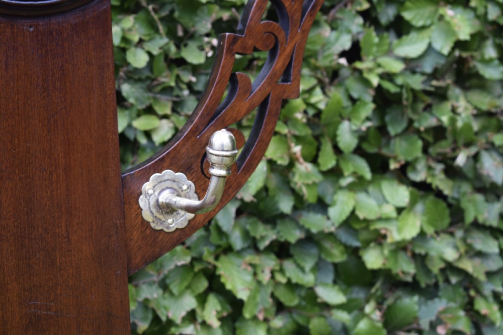 A Victorian walnut hall stand featuring carved fretwork branches, brass coat hooks, a central circular mirror, a glove box, and a lower drip tray base. View XI