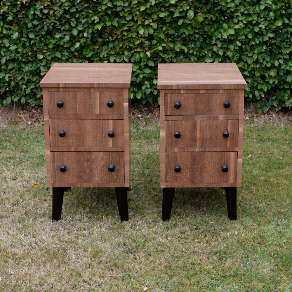 A matching pair of three-drawer walnut bedside chests featuring dark turned knobs and ebonised tapered legs. View II
