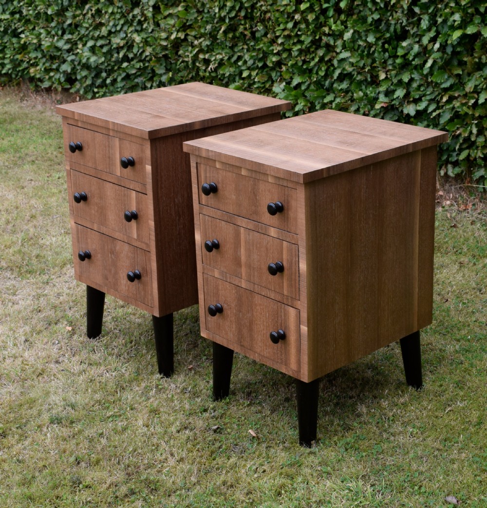 A matching pair of three-drawer walnut bedside chests featuring dark turned knobs and ebonised tapered legs. View V