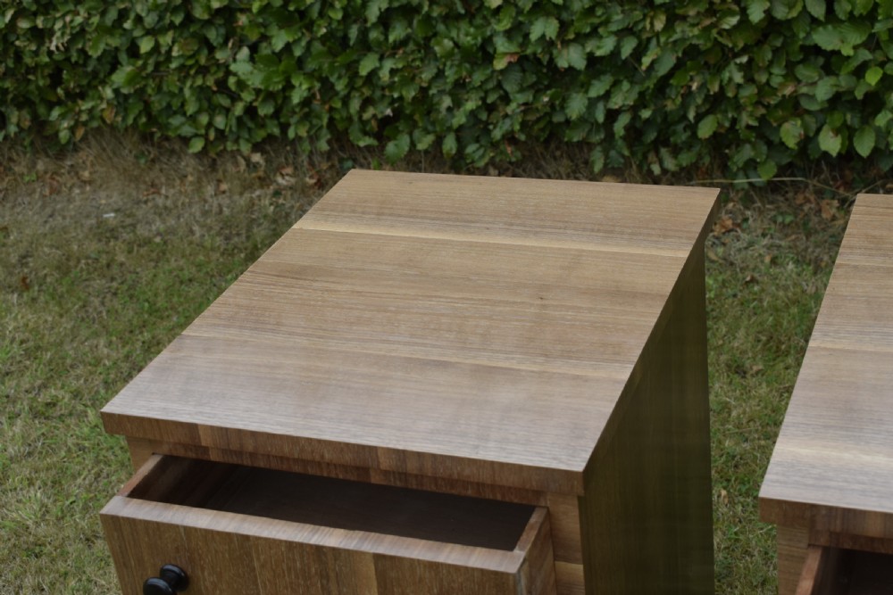 A matching pair of three-drawer walnut bedside chests featuring dark turned knobs and ebonised tapered legs. View X