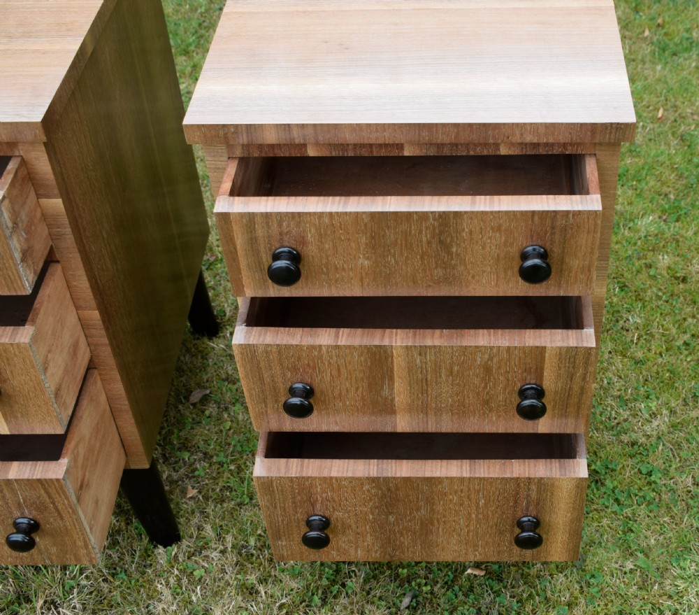 A matching pair of three-drawer walnut bedside chests featuring dark turned knobs and ebonised tapered legs. View XI